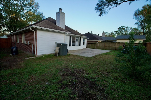 rear view of property with a patio area, a yard, and central AC