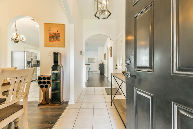 entrance foyer featuring a towering ceiling, light tile patterned flooring, and a chandelier