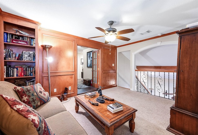 living room featuring ceiling fan, carpet, and ornamental molding