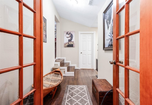 hall featuring french doors, dark hardwood / wood-style flooring, a textured ceiling, and vaulted ceiling