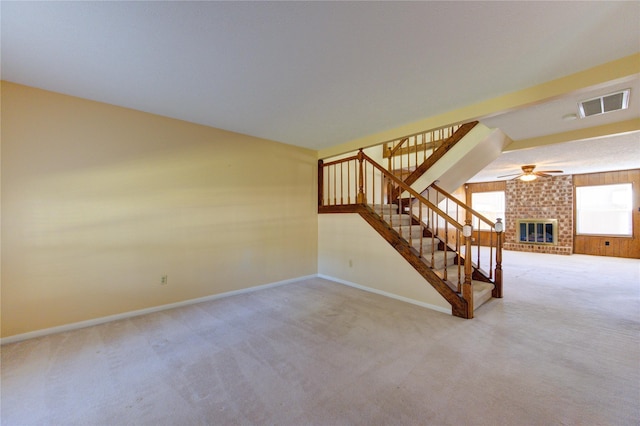 interior space with a fireplace, carpet floors, ceiling fan, and wooden walls