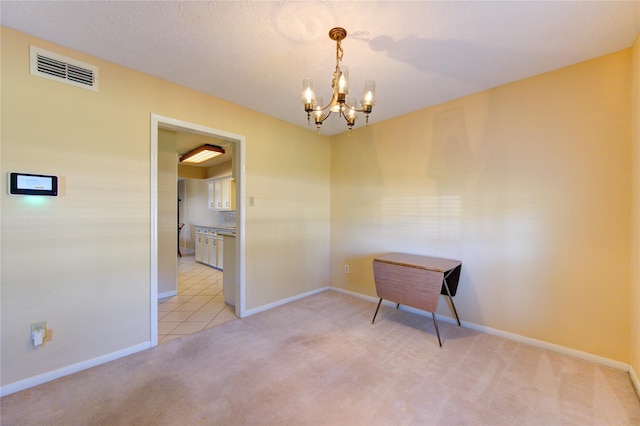 carpeted spare room featuring a notable chandelier and a textured ceiling