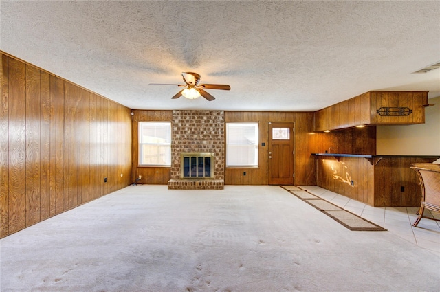 unfurnished living room featuring a textured ceiling, ceiling fan, light colored carpet, and a fireplace