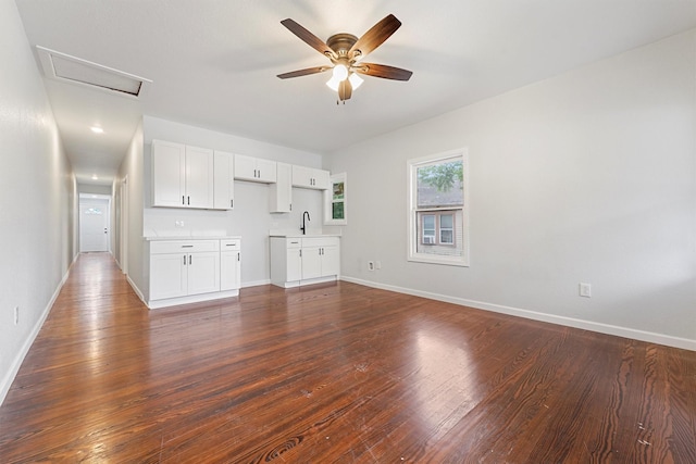 unfurnished living room featuring dark hardwood / wood-style floors, ceiling fan, and sink