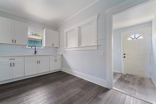 kitchen featuring white cabinets, crown molding, sink, wooden walls, and dark hardwood / wood-style flooring