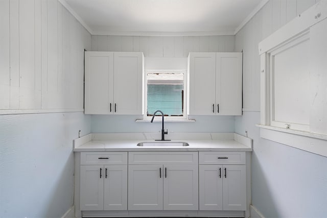 kitchen with white cabinets, ornamental molding, and sink