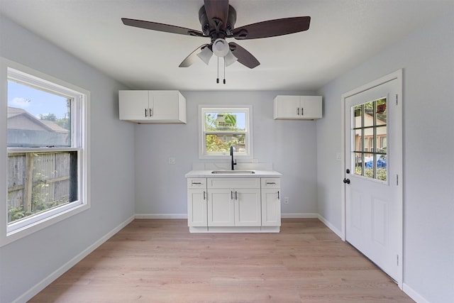 kitchen with light hardwood / wood-style floors, white cabinetry, ceiling fan, and sink