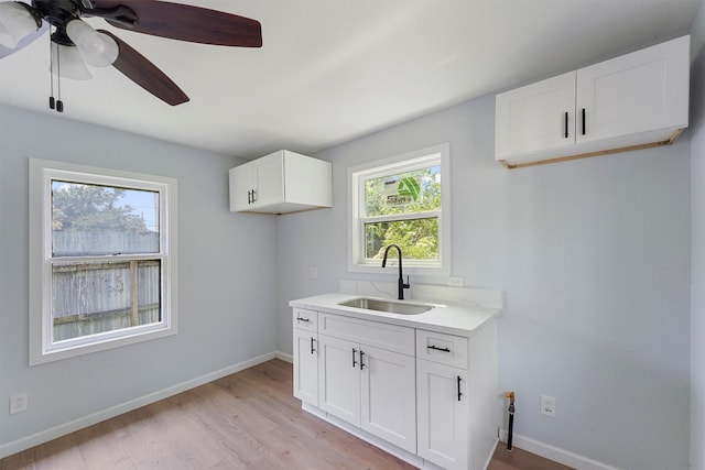 laundry area with ceiling fan, sink, and light wood-type flooring