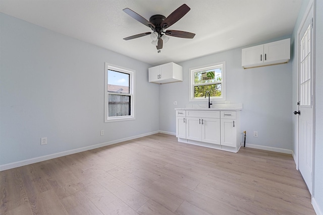 unfurnished room with ceiling fan, light hardwood / wood-style floors, and sink