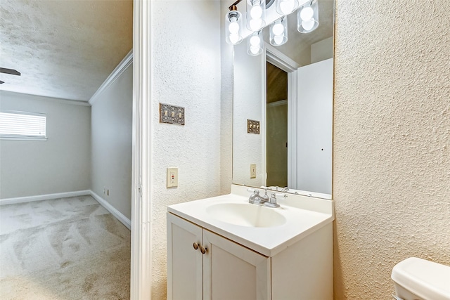 bathroom with toilet, vanity, a textured ceiling, and ornamental molding