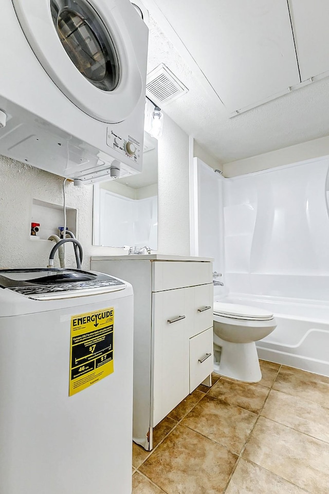 laundry room featuring light tile patterned floors and stacked washing maching and dryer