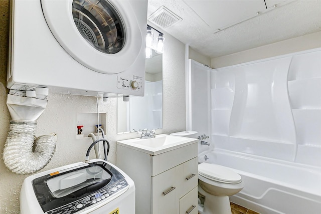 full bathroom with vanity, toilet, stacked washing maching and dryer, a textured ceiling, and tub / shower combination