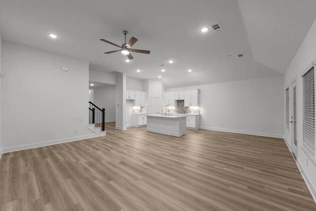 8618 Sun Coral Dr, Cypress, TX 77433 - unfurnished living room with a sink, stairway, visible vents, ceiling fan, and vaulted ceiling
