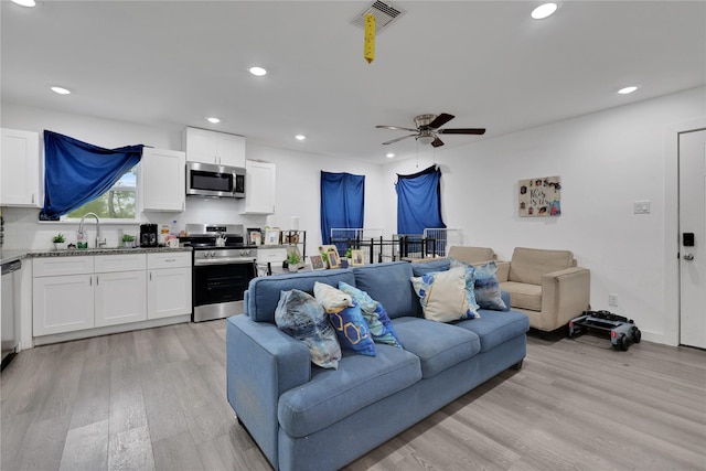 living room featuring ceiling fan, sink, and light hardwood / wood-style floors