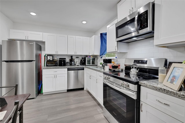 kitchen with appliances with stainless steel finishes, light hardwood / wood-style flooring, and white cabinetry