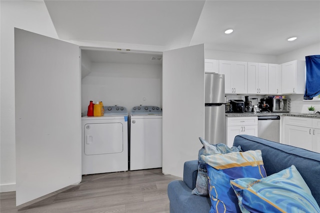 clothes washing area with separate washer and dryer and light hardwood / wood-style floors