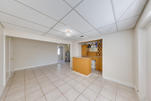 kitchen with water heater, a drop ceiling, and light tile patterned flooring