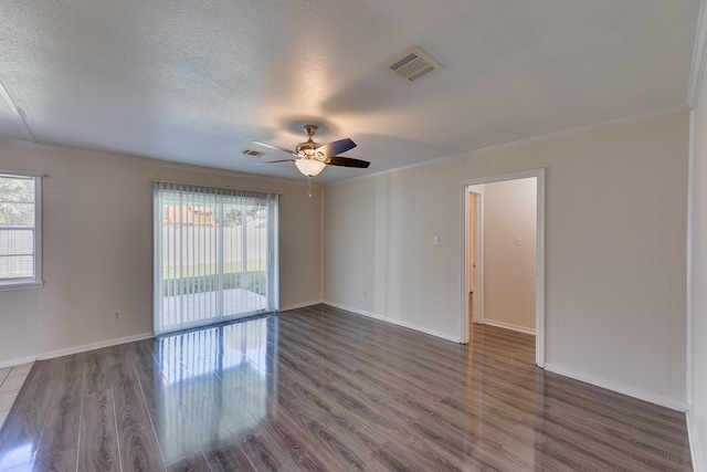 empty room with a textured ceiling, ceiling fan, crown molding, and dark wood-type flooring