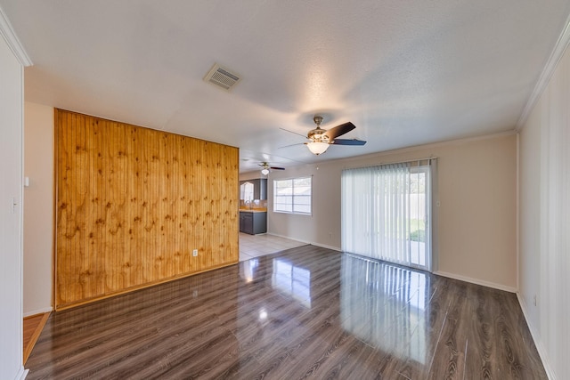 unfurnished room with hardwood / wood-style flooring, ornamental molding, a textured ceiling, and wooden walls