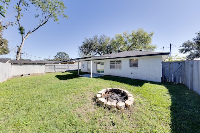 back of house with a fire pit and a yard