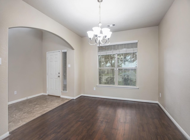 empty room featuring dark hardwood / wood-style flooring and a chandelier