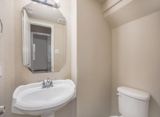 bathroom with sink, lofted ceiling, and toilet