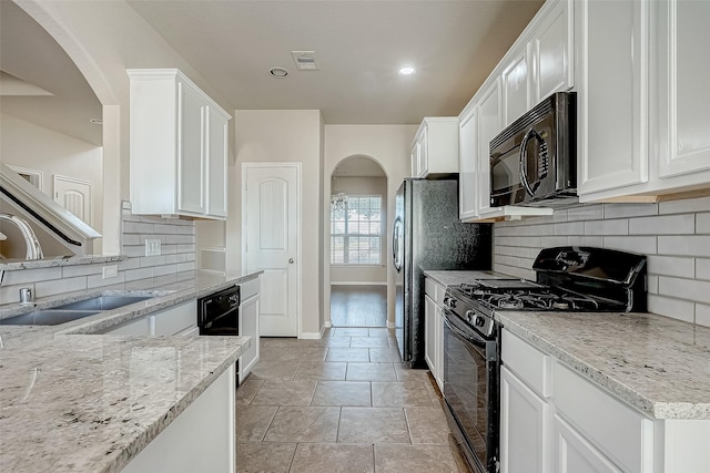 kitchen featuring black appliances, backsplash, white cabinets, and light stone counters