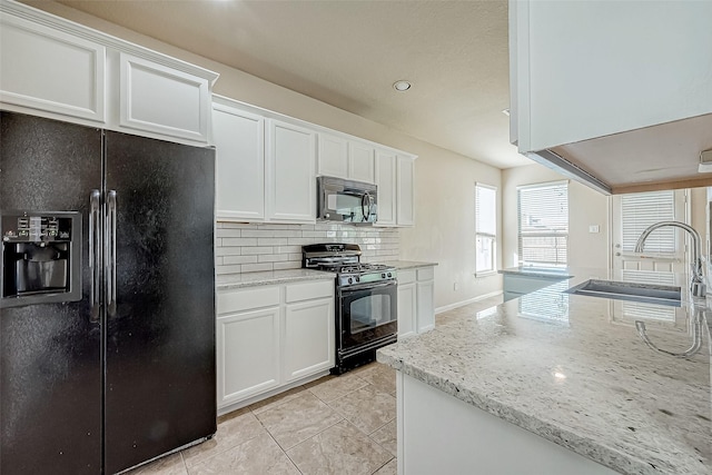 kitchen with white cabinets, sink, light stone countertops, and black appliances