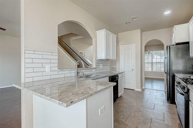 kitchen featuring decorative backsplash, light stone countertops, sink, range, and white cabinetry