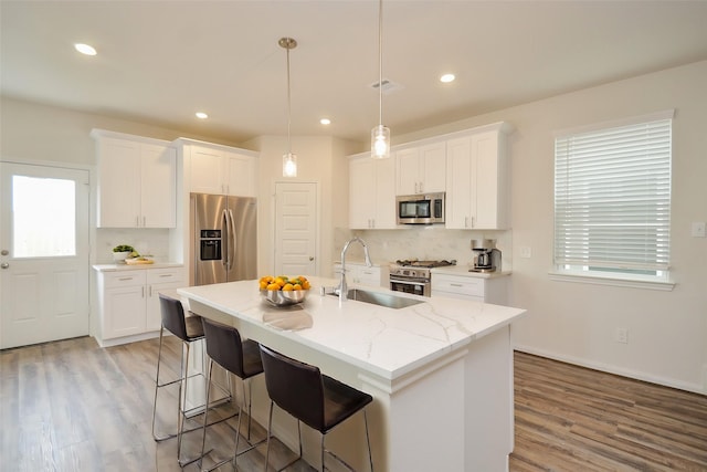 14983 Eagle Feather Dr, Houston, TX 77090 - kitchen with light wood-style flooring, white cabinetry, an island with sink, and stainless steel appliances