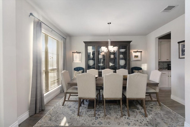 dining space with hardwood / wood-style flooring, plenty of natural light, and a chandelier