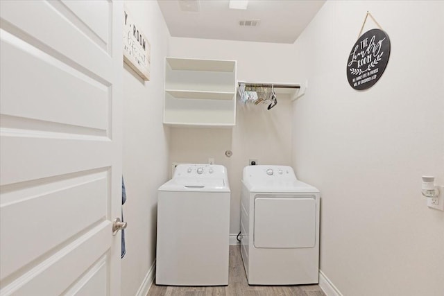 laundry area with washer and clothes dryer and light hardwood / wood-style flooring