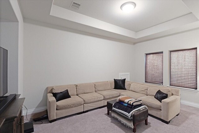 carpeted living room featuring a tray ceiling