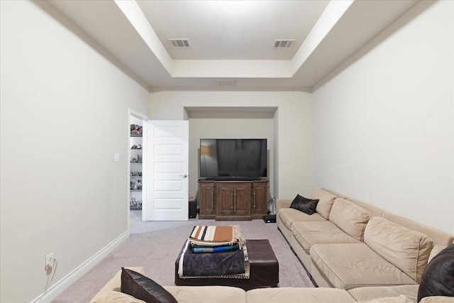 carpeted living room with a tray ceiling