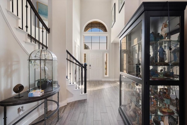 entryway with dark wood-type flooring, a high ceiling, baseboards, and stairs