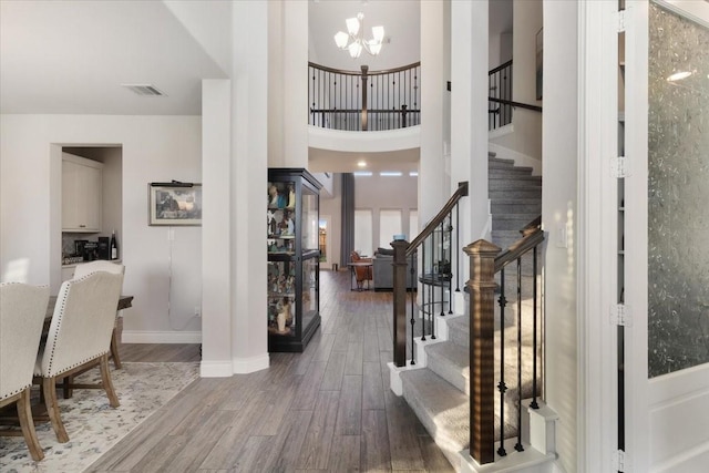 entryway with a towering ceiling, dark wood-type flooring, and a notable chandelier