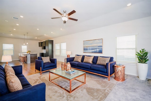 living room with ceiling fan, vaulted ceiling, and light wood-type flooring