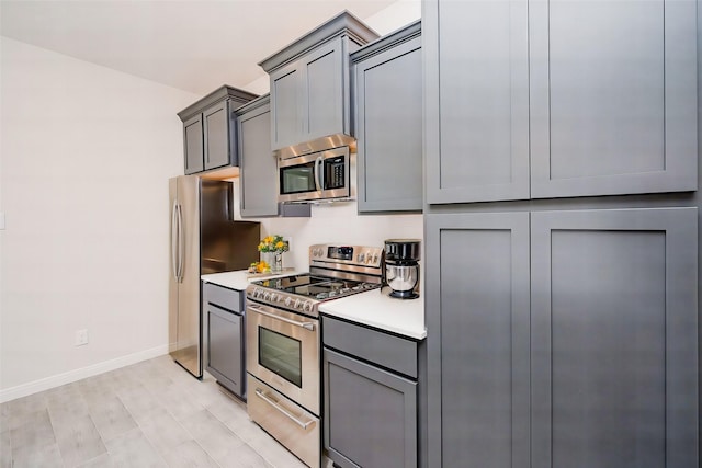 kitchen featuring appliances with stainless steel finishes, gray cabinets, and light hardwood / wood-style flooring