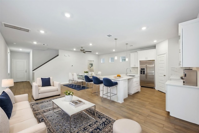 living room featuring sink, light hardwood / wood-style floors, and ceiling fan