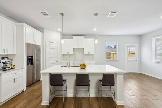 kitchen with decorative light fixtures, high end refrigerator, and an island with sink