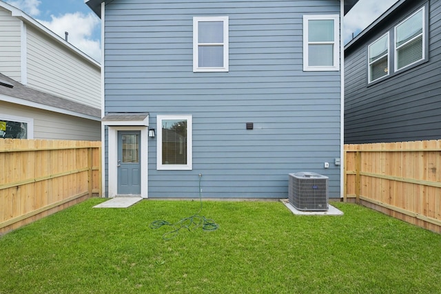 rear view of house featuring cooling unit and a lawn