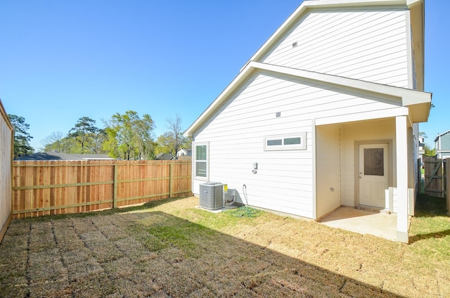 back of house featuring a fenced backyard, a lawn, and central AC