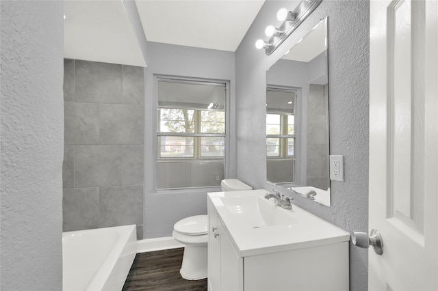 bathroom featuring a washtub, vanity, wood-type flooring, and toilet