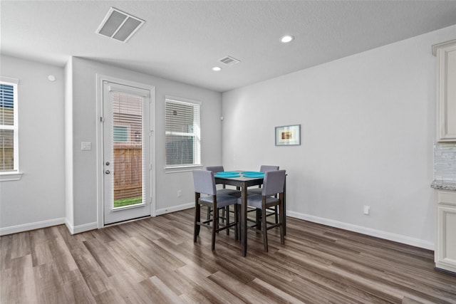 dining area with wood-type flooring and a textured ceiling