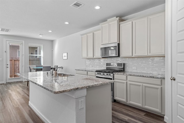 kitchen with sink, appliances with stainless steel finishes, dark hardwood / wood-style flooring, and an island with sink