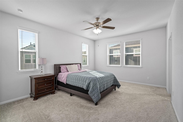 bedroom featuring ceiling fan, light carpet, and multiple windows