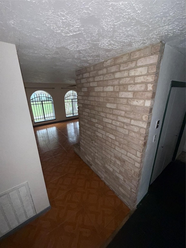 corridor featuring parquet floors and a textured ceiling