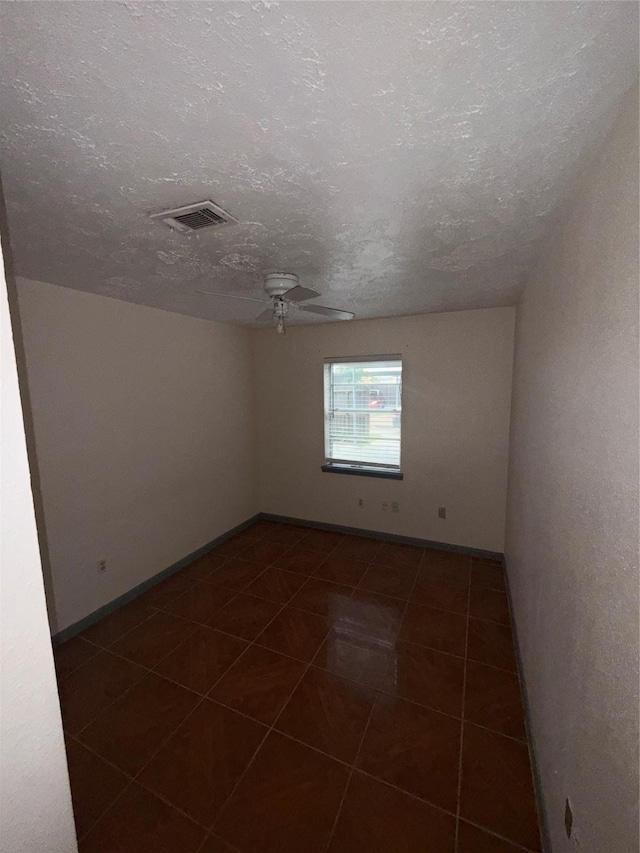 tiled empty room with ceiling fan and a textured ceiling