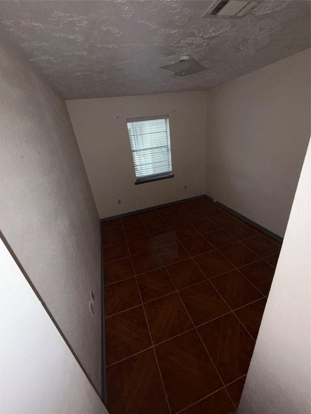 unfurnished room featuring dark tile patterned floors and a textured ceiling