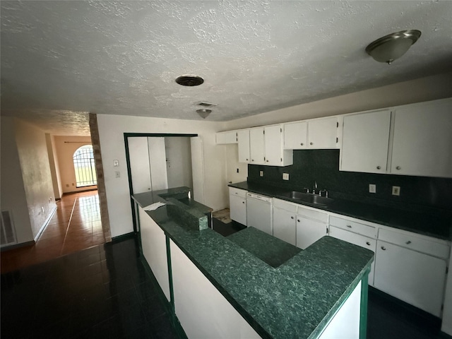 kitchen with sink, tasteful backsplash, a textured ceiling, white cabinets, and dark tile patterned flooring